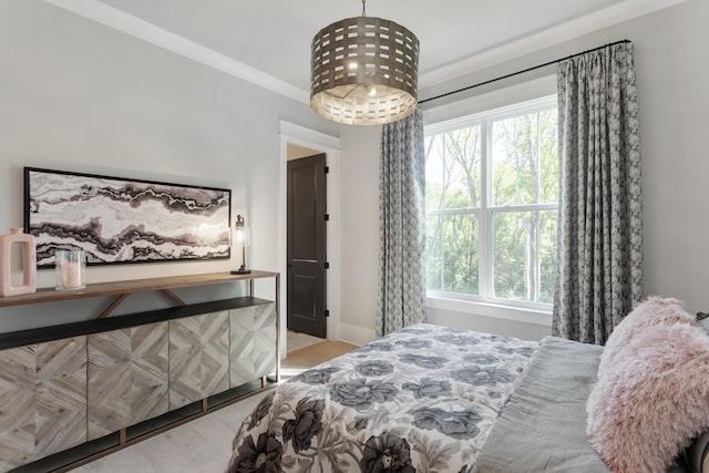 bedroom featuring multiple windows, ornamental molding, and light hardwood / wood-style floors