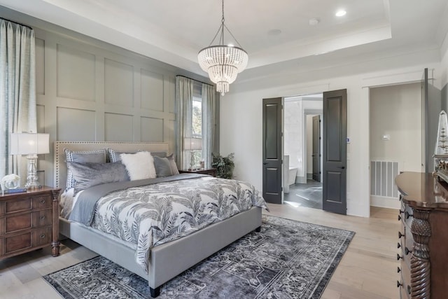 bedroom featuring a raised ceiling, crown molding, a notable chandelier, and light hardwood / wood-style floors