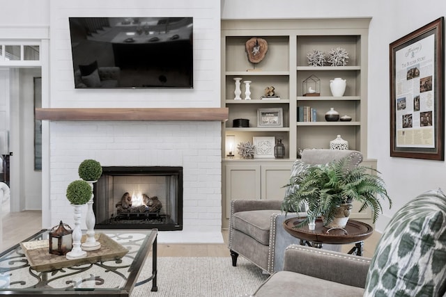 living room featuring a brick fireplace and light hardwood / wood-style flooring