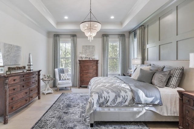 bedroom with multiple windows, a tray ceiling, an inviting chandelier, and light wood-type flooring