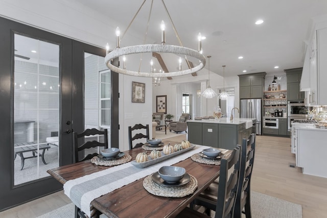 dining space featuring a notable chandelier, light hardwood / wood-style floors, and french doors