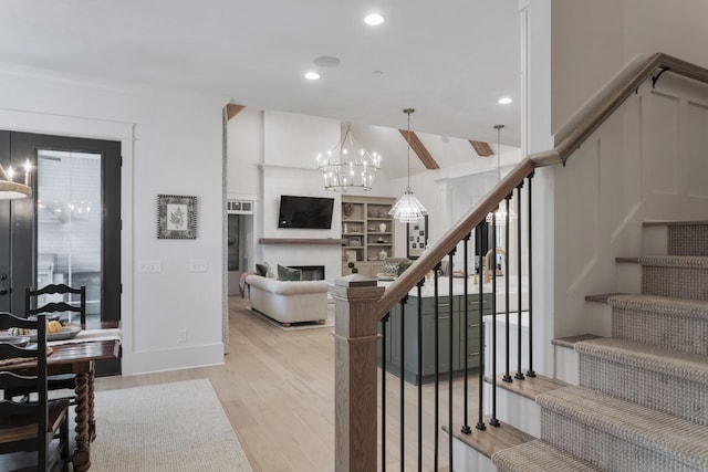 stairs featuring hardwood / wood-style flooring, vaulted ceiling, a chandelier, and built in shelves