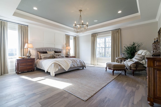 bedroom with hardwood / wood-style flooring, a chandelier, and a tray ceiling