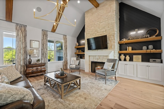 living room with a fireplace, a wealth of natural light, light hardwood / wood-style flooring, and beamed ceiling