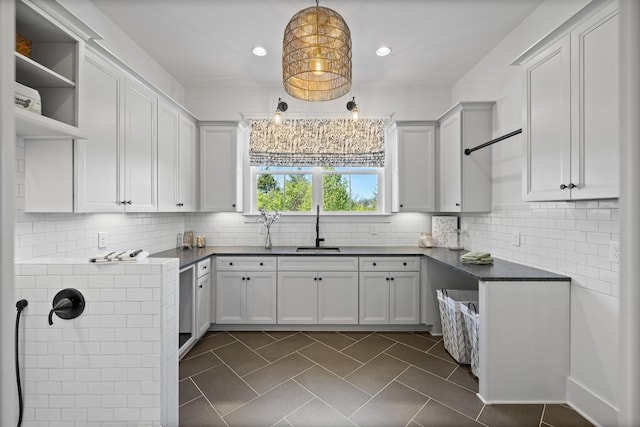 kitchen with tasteful backsplash, decorative light fixtures, sink, and white cabinets