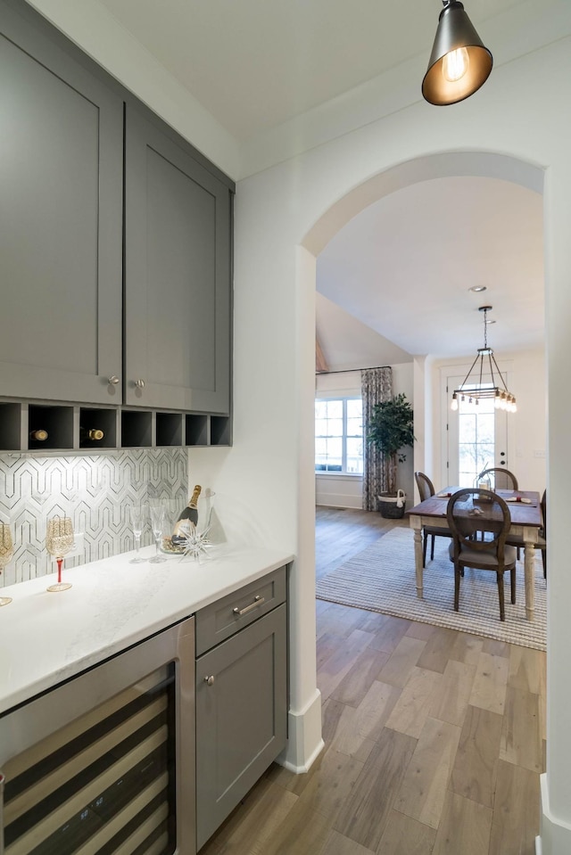 bar featuring gray cabinetry, hanging light fixtures, wine cooler, tasteful backsplash, and light hardwood / wood-style floors