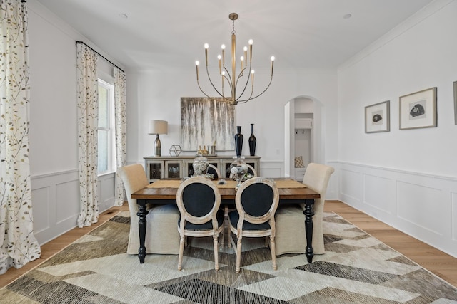 dining space with a notable chandelier, ornamental molding, and light wood-type flooring