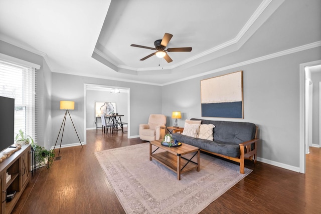 living room with crown molding, dark hardwood / wood-style floors, a raised ceiling, and ceiling fan