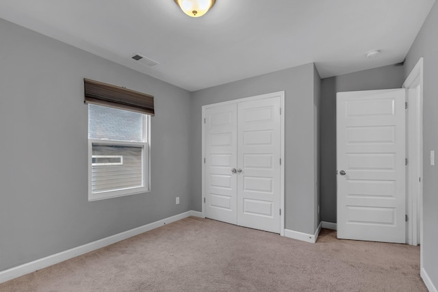 unfurnished bedroom with light carpet and a closet