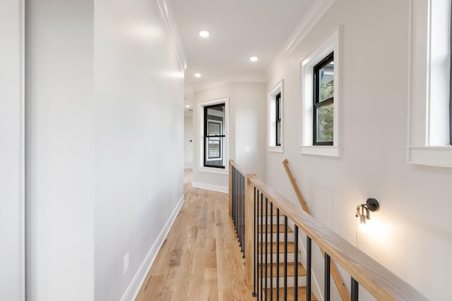 hallway featuring baseboards, ornamental molding, an upstairs landing, light wood-type flooring, and recessed lighting