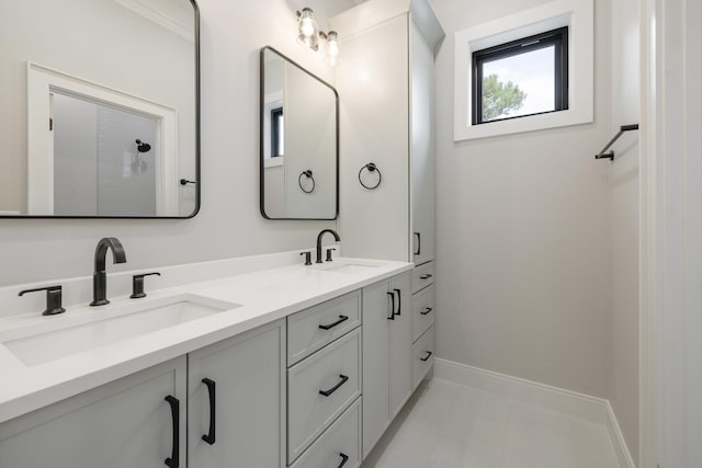 bathroom with double vanity, baseboards, a sink, and tile patterned floors