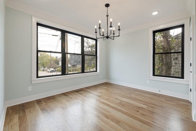 empty room with crown molding, baseboards, an inviting chandelier, and light wood-style floors