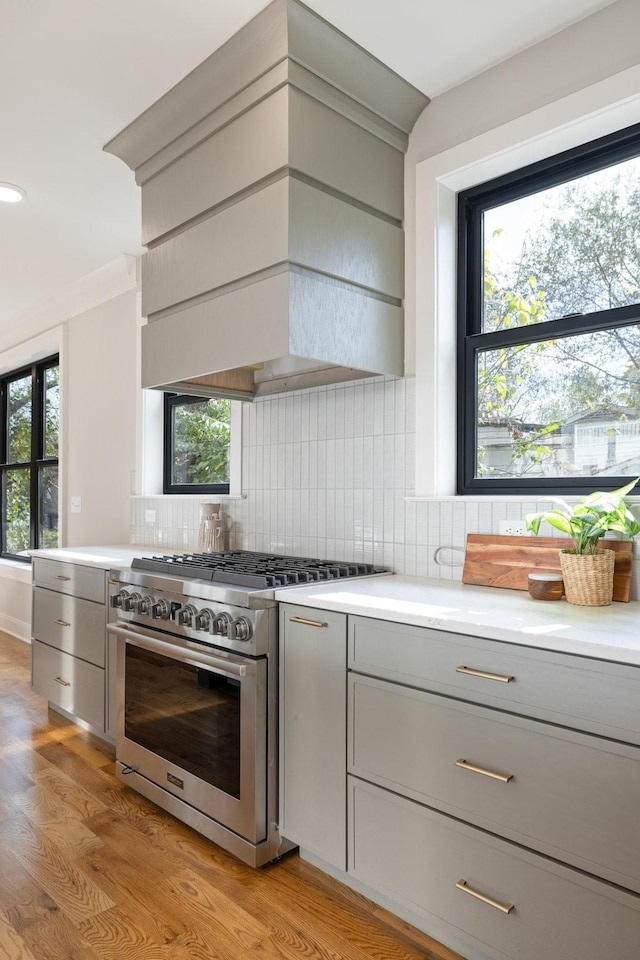 kitchen with high end stainless steel range oven, light countertops, light wood finished floors, and gray cabinetry