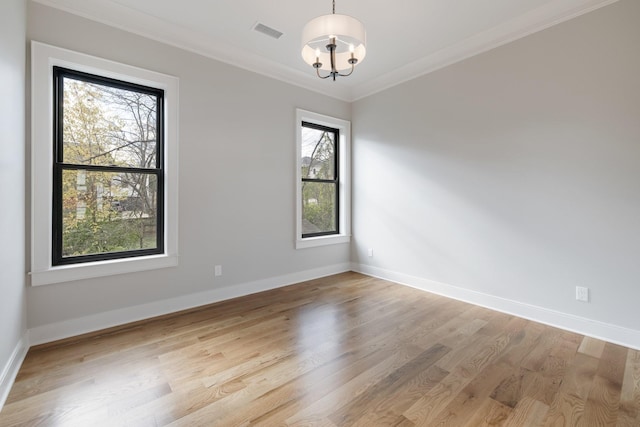 unfurnished room featuring visible vents, light wood-style flooring, ornamental molding, a chandelier, and baseboards