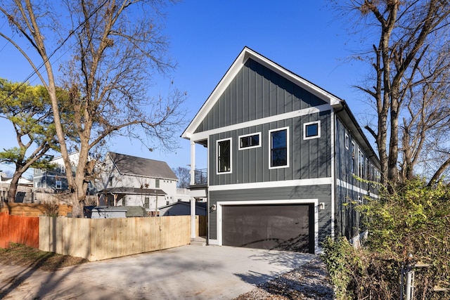 view of front of house featuring a garage, board and batten siding, fence, and concrete driveway