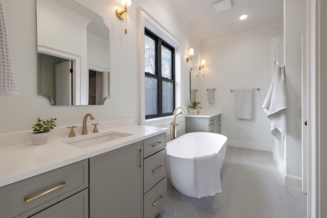 bathroom featuring crown molding, a freestanding bath, two vanities, and a sink