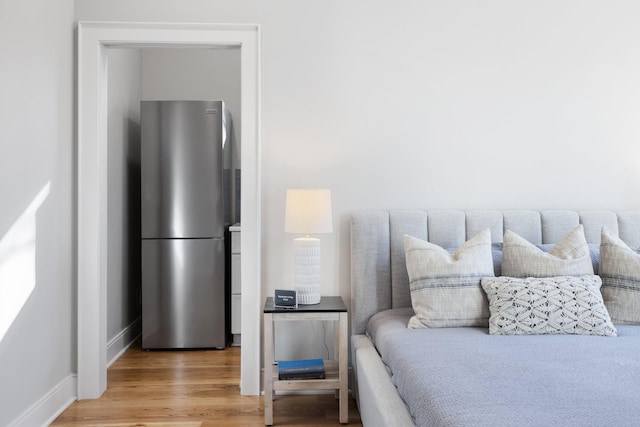 bedroom featuring light wood-style flooring, baseboards, and freestanding refrigerator