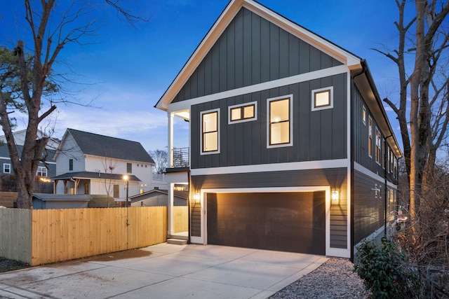 view of front of home with driveway, board and batten siding, an attached garage, and fence