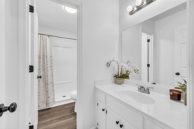 bathroom featuring wood-type flooring, toilet, a shower with shower curtain, and vanity