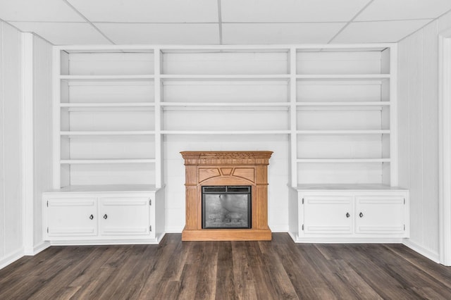 unfurnished living room featuring a paneled ceiling, dark hardwood / wood-style floors, and built in features