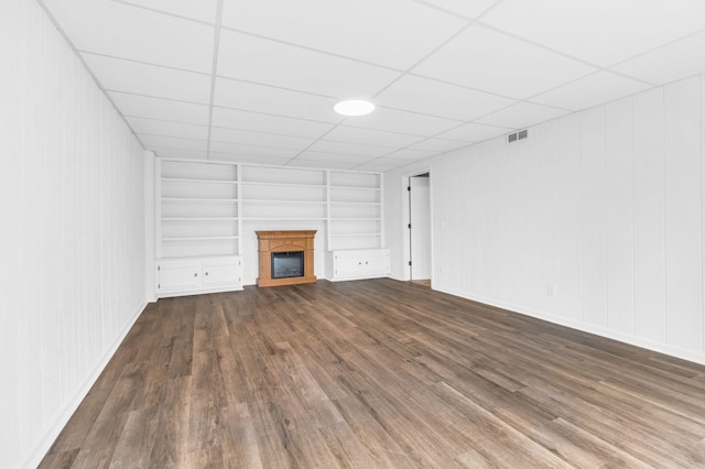 unfurnished living room with dark hardwood / wood-style flooring and built in shelves