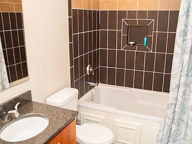 full bathroom with toilet, vanity, and shower / bathtub combination with curtain