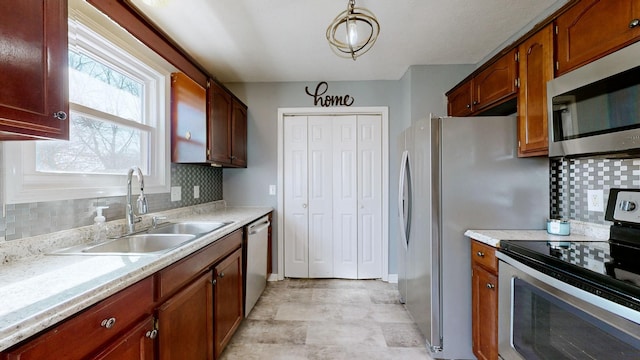 kitchen with tasteful backsplash, appliances with stainless steel finishes, sink, and hanging light fixtures