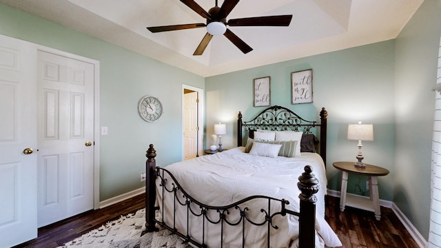 bedroom featuring dark wood-type flooring, ceiling fan, and a tray ceiling