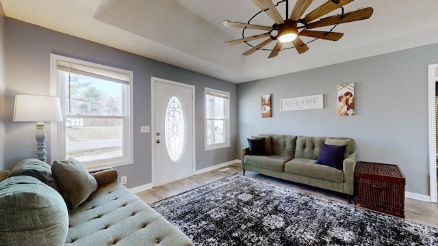 living room with a tray ceiling, plenty of natural light, and ceiling fan