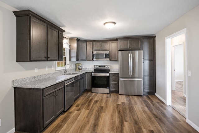 kitchen with sink, appliances with stainless steel finishes, dark brown cabinetry, and dark hardwood / wood-style flooring