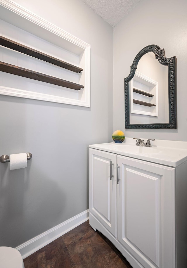 bathroom with toilet, vanity, and a textured ceiling