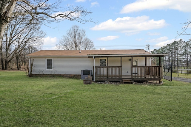 rear view of house featuring cooling unit, a lawn, and a wooden deck