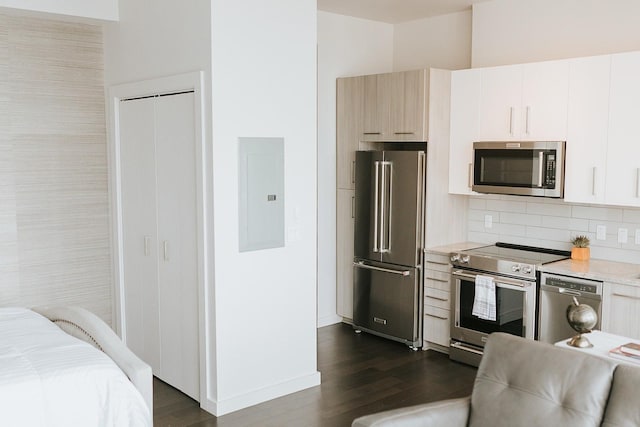 kitchen featuring stainless steel appliances, dark wood-type flooring, white cabinets, and electric panel