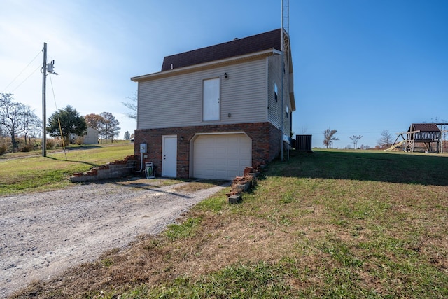 exterior space with a garage, central AC unit, and a front lawn