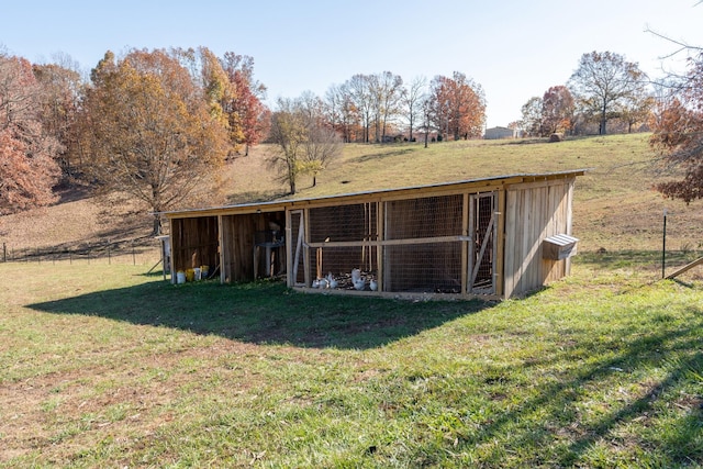 back of house with an outbuilding, a yard, and a rural view