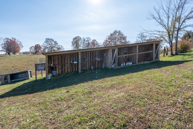 rear view of property featuring a yard, an outbuilding, and a rural view