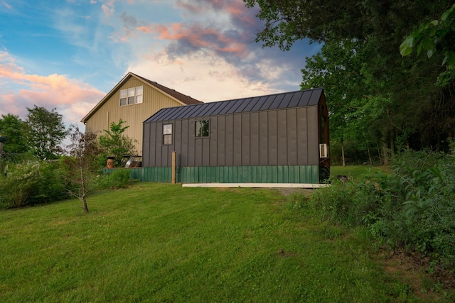 property exterior at dusk with a standing seam roof, a lawn, and metal roof