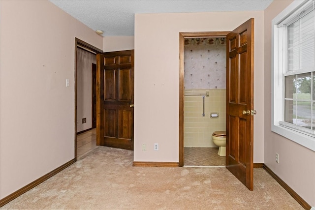 1144 Miller Rd, Lewisburg, TN 37091 - unfurnished bedroom with light carpet, baseboards, ensuite bathroom, a textured ceiling, and tile walls