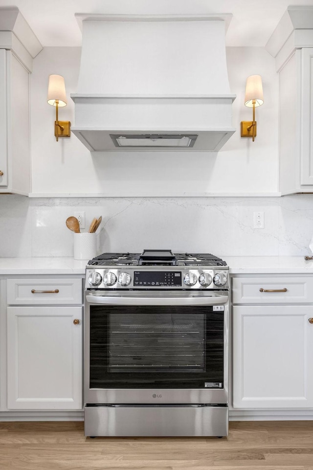 kitchen with white cabinetry, custom range hood, light hardwood / wood-style flooring, and stainless steel range with gas stovetop