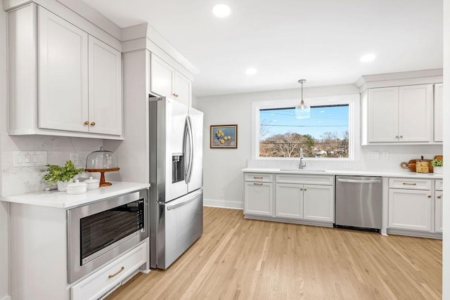 kitchen featuring white cabinetry, appliances with stainless steel finishes, decorative light fixtures, and sink