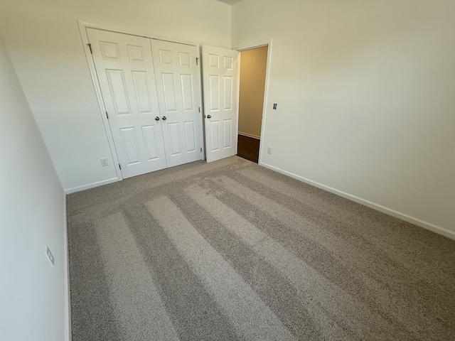 unfurnished bedroom with a closet, baseboards, and carpet