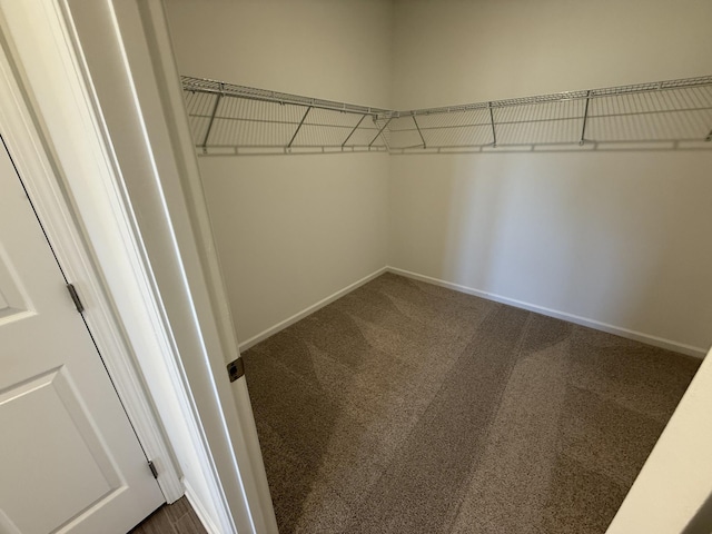 walk in closet featuring dark carpet