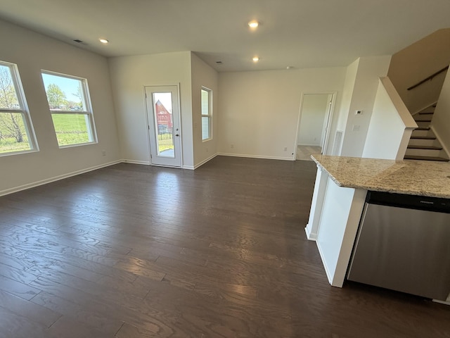 unfurnished living room featuring a wealth of natural light, stairs, dark wood-style floors, and baseboards