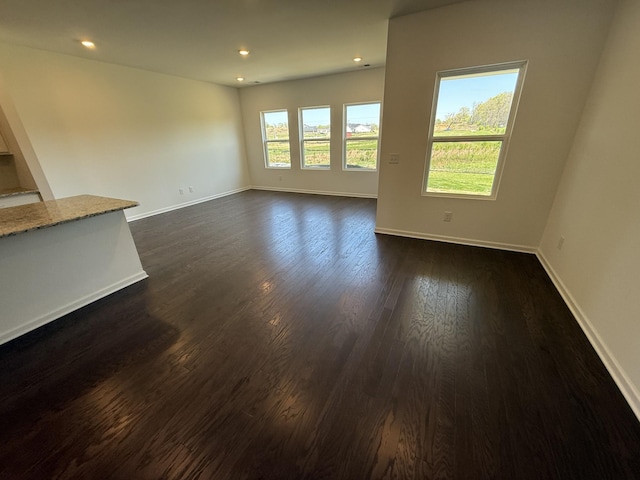 unfurnished living room with dark wood-type flooring, baseboards, and recessed lighting
