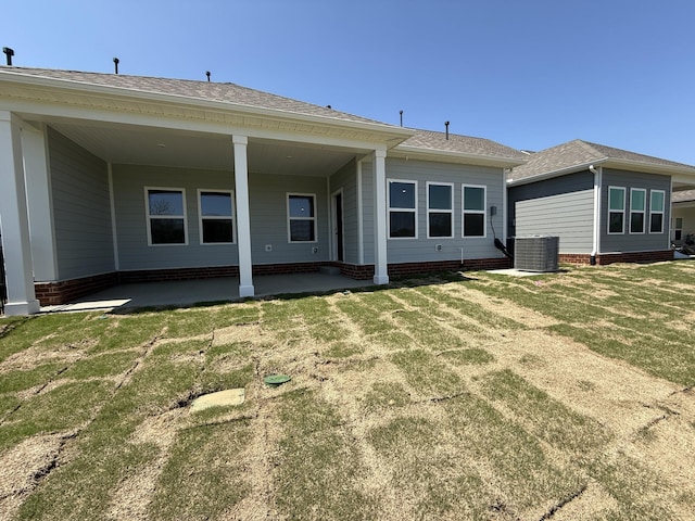rear view of property with a patio, central air condition unit, and a yard