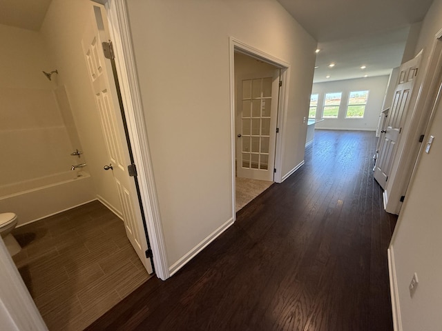 corridor with dark wood-style flooring, baseboards, and recessed lighting