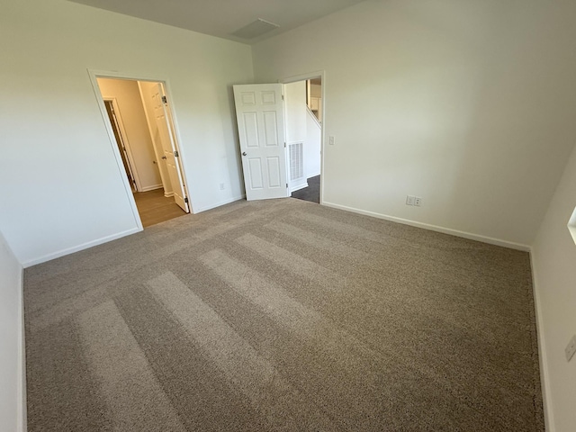 unfurnished bedroom featuring dark colored carpet, visible vents, baseboards, and connected bathroom