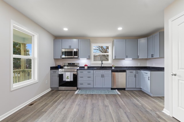 kitchen with appliances with stainless steel finishes, dark countertops, visible vents, and light wood-style flooring