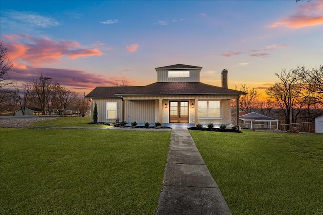 view of front facade with a porch, a yard, and french doors