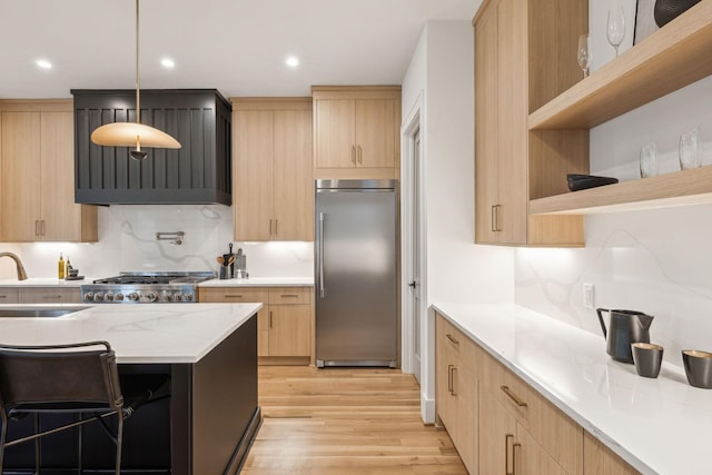 kitchen featuring light brown cabinetry, sink, decorative light fixtures, light hardwood / wood-style flooring, and built in fridge